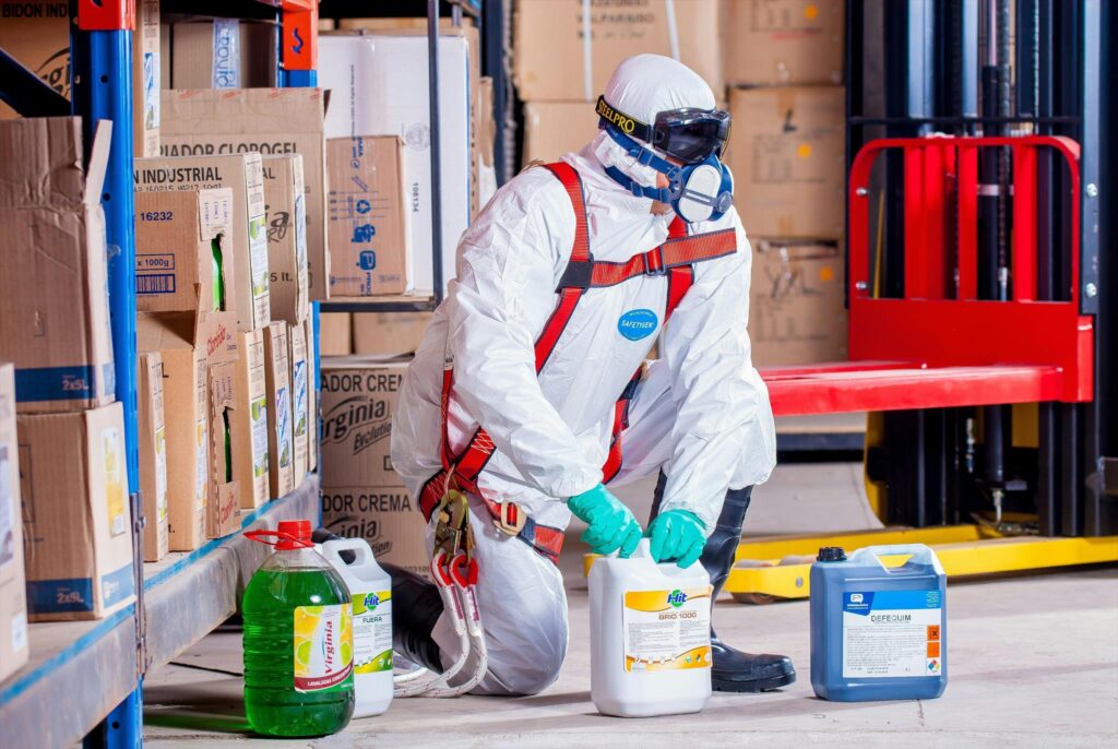 A worker wearing a full protective suit, including a respirator mask, gloves, and safety goggles.