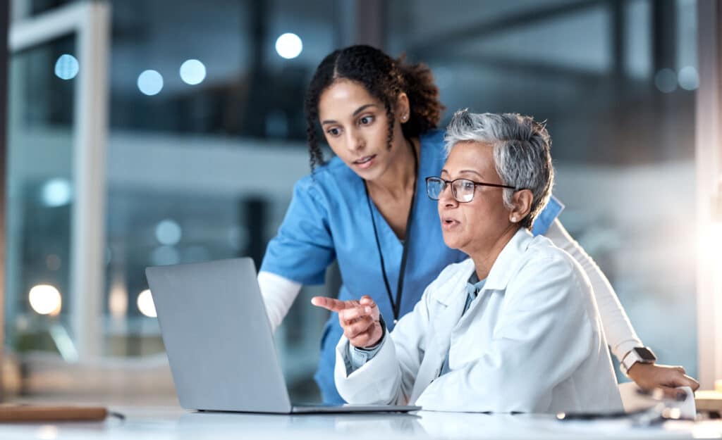 Two healthcare professionals collaborating on a laptop.