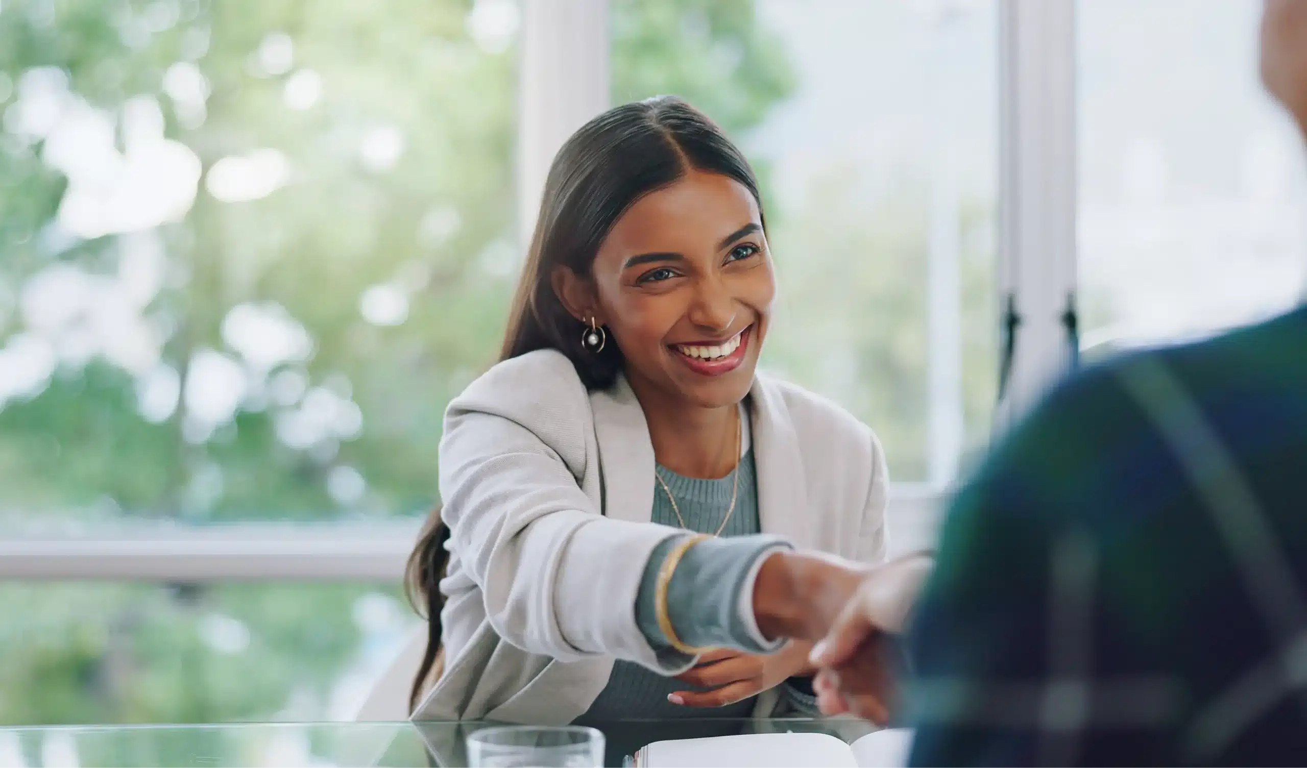 Professional woman happily shaking hands with person across from her