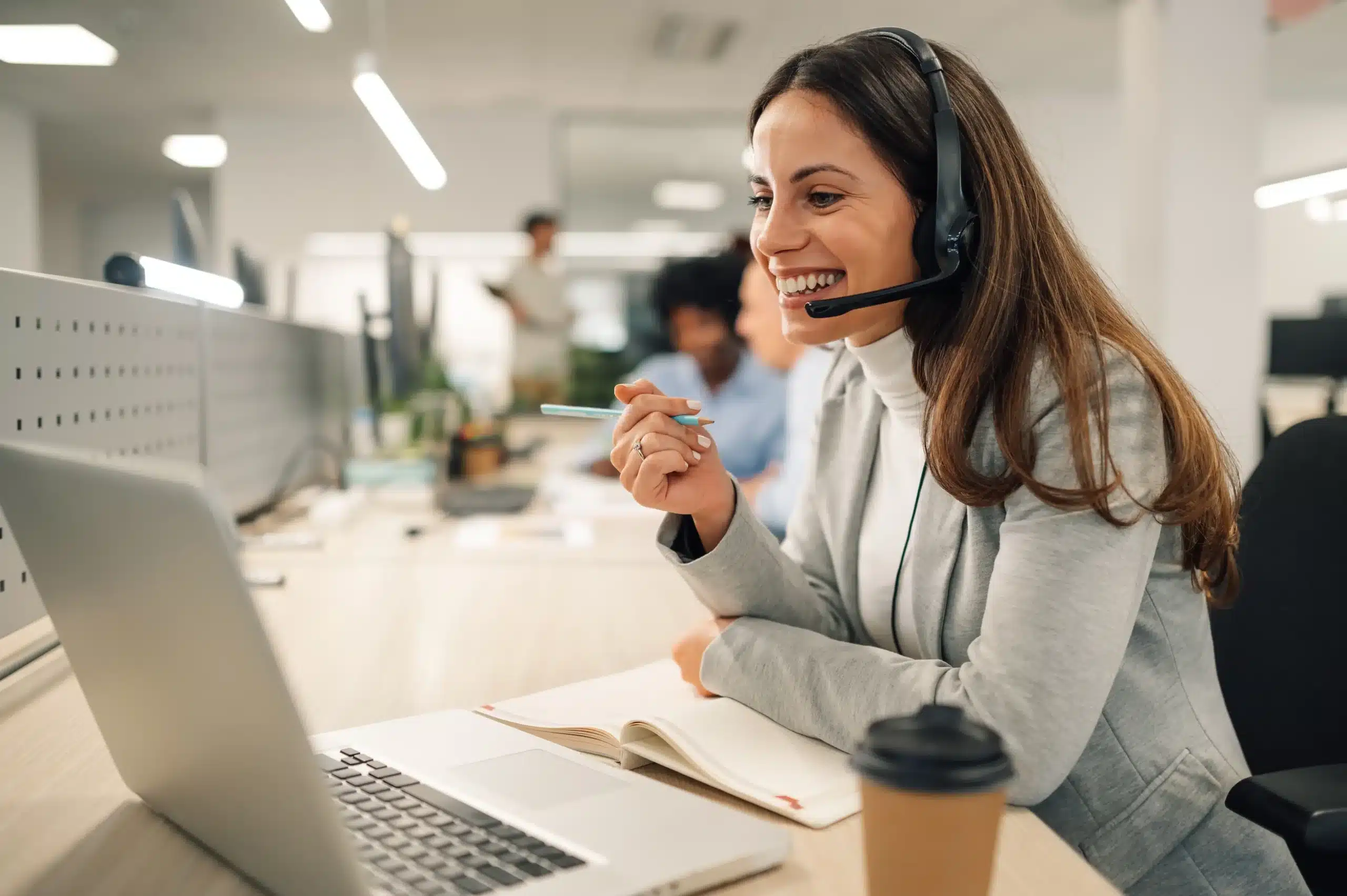 woman with headphones smiling at computer