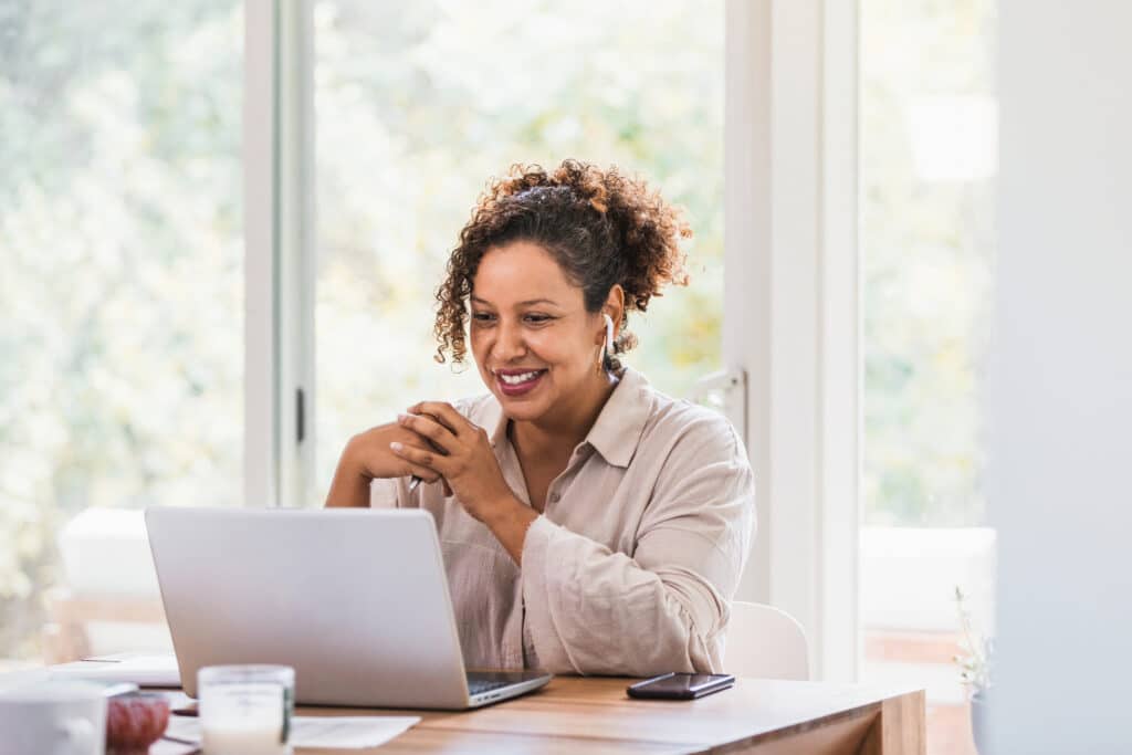 Businesswoman sitting at a table typing on a laptop.